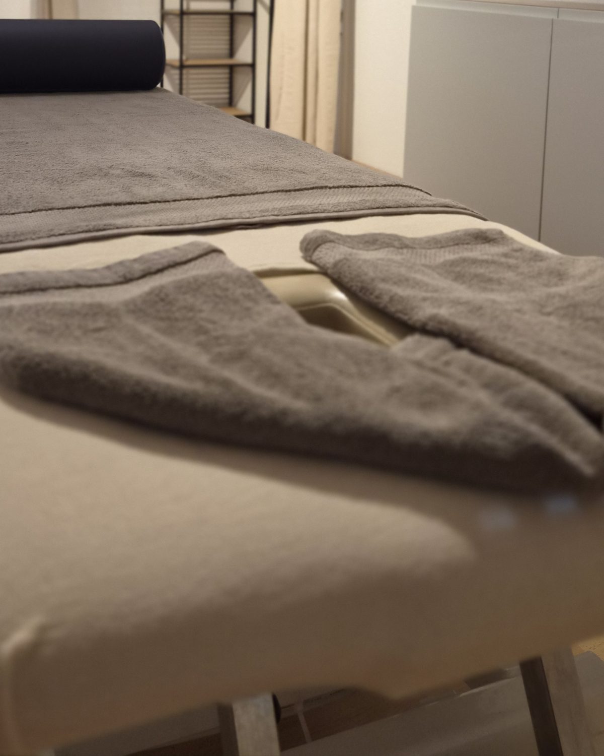 Frisch gefaltete Tücher und Nackenrolle auf der Massageliege