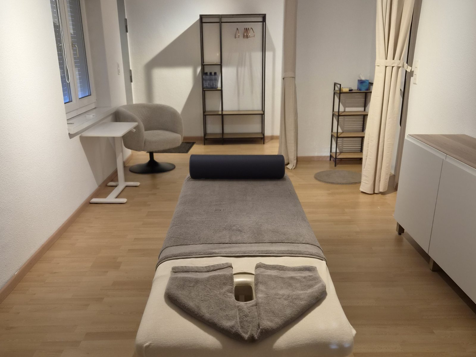 Behandlungsraum der Massagepraxis ONE mit Massageliege und Tageslicht